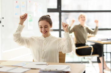 Office workers raise fists in triumph rejoicing at success