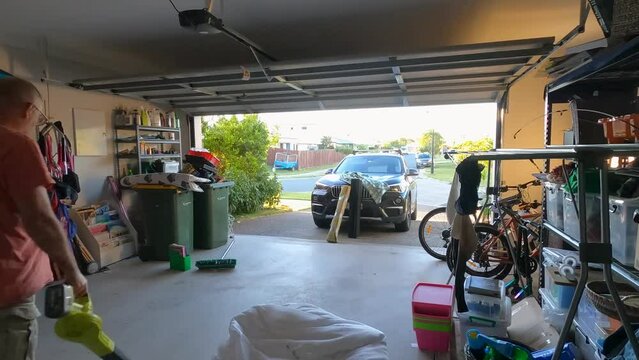 A mature couple is tidying up cluttered a double garage.