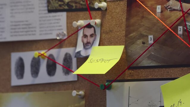 Detective placing a note next to the suspect's photo on the evidence board