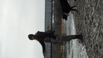Vertical: Man in chest waders casts fly rod, fishing in river with dog - Powered by Adobe