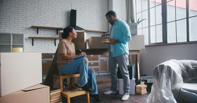 Man and woman put books into boxes for moving from house