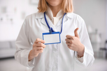 Fototapeta premium Female doctor with badge showing thumb-up in modern clinic