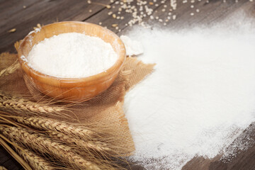 Soft focus, flour in a wooden bowl, ears of wheat, barley, cooking, bread, and cookies arranged on a wooden tabletop in a rustic kitchen, top view.