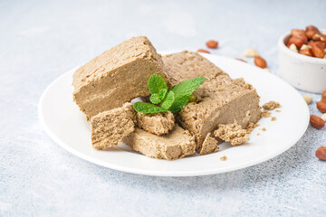 Plate with pieces of tasty halva on light background