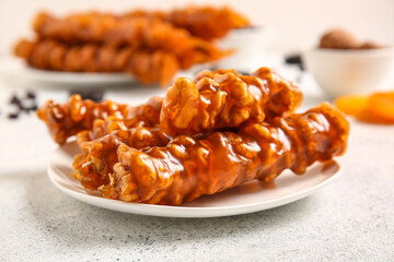 Plate with sweet churchkhela on light background