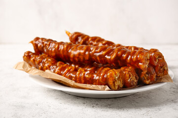 Plate with sweet churchkhela on light background