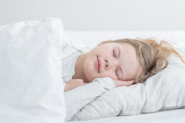 Obraz na płótnie Canvas Happy little girl sleeps on the bed at home