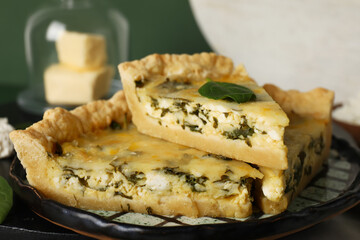 Plate with pieces of delicious quiche on green background