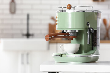 Modern coffee machine with cup and beans on white table in kitchen