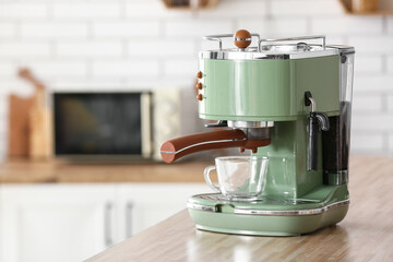 Modern coffee machine with cup and beans on wooden kitchen counter