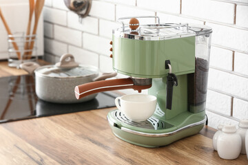 Modern coffee machine with cup and beans on wooden kitchen counter