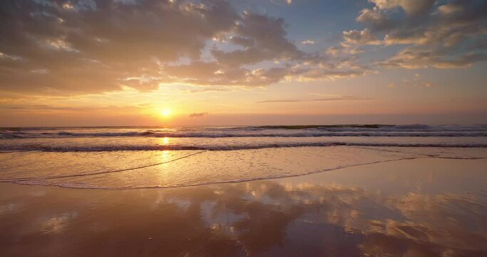 Tropical beach sunrise with golden sun rays over the sand and sea