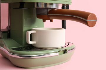 Modern coffee machine with cup on pink background, closeup
