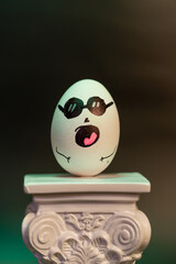 Animated egg with drawings of different faces and expressions mounted on a column in a large photograph
