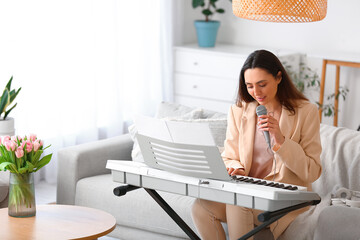 Young female musician playing synthesizer and singing at home