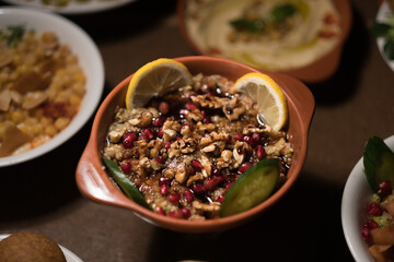 Roasted eggplant ('baba ganoush') topped with walnuts, lemon slices, and cucumber slices, served Syrian style..