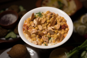 A popular Syrian dish, chickpea fatteh (fried pita with toppings) is served with a garnish of sliced almonds and bits of parsley.