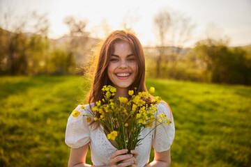 Beautiful woman in a white dress with a bouquet of yellow wildflowers walking in a field 