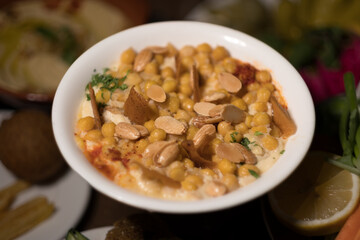 Served Syrian-style, a warm dish made of chickpeas and yogurt is served with slices of fried pita, and slivered almonds.