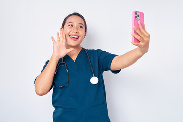 Smiling friendly young Asian woman nurse working wearing blue uniform making video call on...