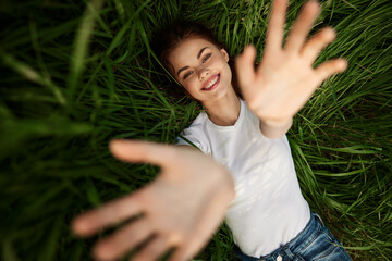 laughing redhead woman stretching her palms to the camera while lying on the grass