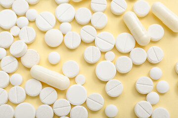 White pills on yellow background, closeup