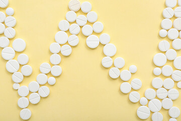 Cardiogram made of white pills on yellow background