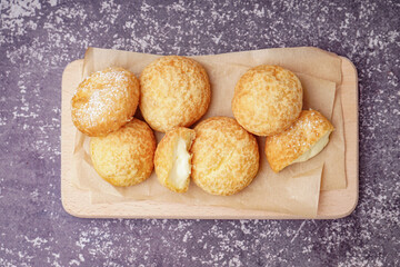 Wooden board with tasty choux dessert on grunge background