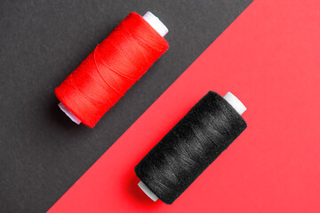 Two thread spools on red background