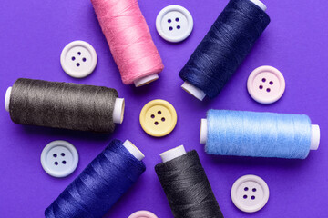 Composition with thread spools and buttons on color background, closeup