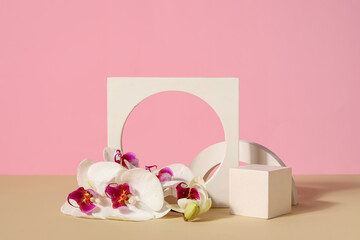 Decorative plaster podiums and beautiful orchid flowers on beige table against pink background