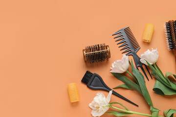 Composition with hairdresser tools and tulip flowers on orange background