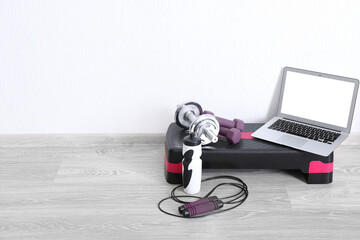 Laptop with sports equipment near white wall in gym