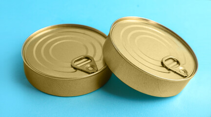 Tin cans with fish on blue background, closeup