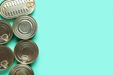 Assortment of tin cans with fish on turquoise background