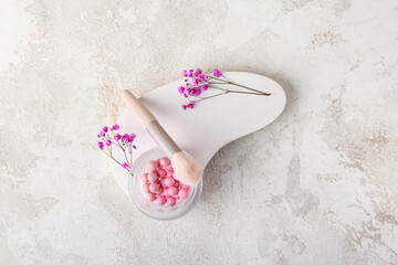 Plaster podium with jar of powder pearls, brush and gypsophila flowers on white grunge background