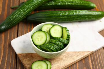 Bowl with fresh cut cucumber on wooden background
