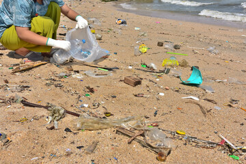 Female volunteers pick up beach trash and put plastic bottles in it.  Put garbage bags. According to the concept of World Environment Day. Earth Day.  photo view below