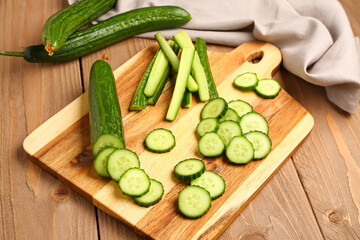 Board with cut cucumber on wooden background