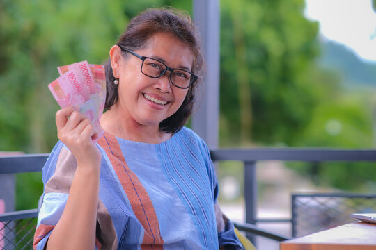 A middle-aged woman showing some money happily