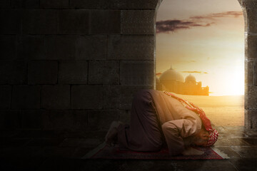 Muslim man with a beard wearing keffiyeh with agal in praying position (salat) on the prayer rug