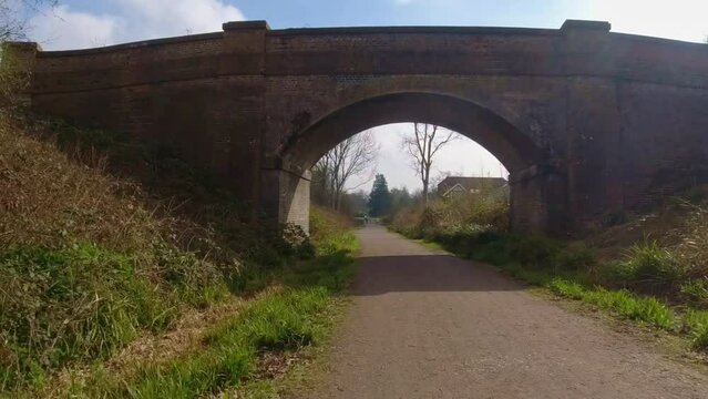 Riding through a small stone bridge across a gravel track through the English countryside