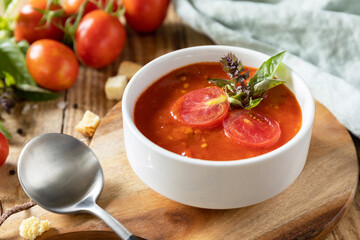 Bowl of tomato cream soup with basil and croutons on a rustic table. Vegan soup puree tomatoes. Healthy diet low carb.