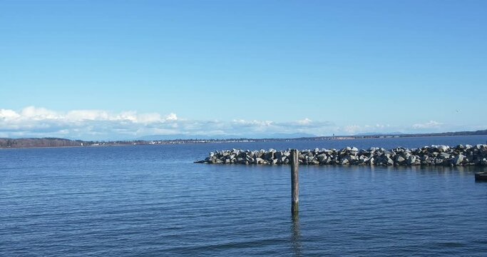 Seascape in sunny day, White Rock, BC, Canada. Shore, rocks, blue sky seen in footage