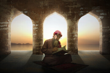 Muslim man with a beard wearing keffiyeh with agal sitting and reading the Quran on the prayer rug