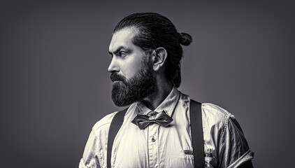 Fototapeta premium Closeup of a gentleman his bowtie. Beard man in bow tie and suspenders. Portrait of handsome bearded man in white shirt and bow tie, suspenders. Black and white