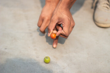 A fruit in one hand and another on the ground