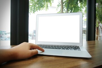 Laptop with blank screen on wooden table in front of coffeeshop cafe - technology concept