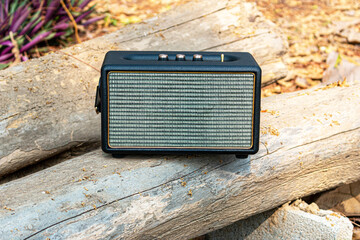black portable wireless speaker on natural timber background, vintage speakers