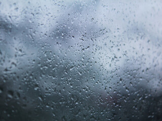 Water drops and raindrops on transparent window for background and design. Rain gray blue clouds glass texture. A lots of small wet spots and sprinkle.